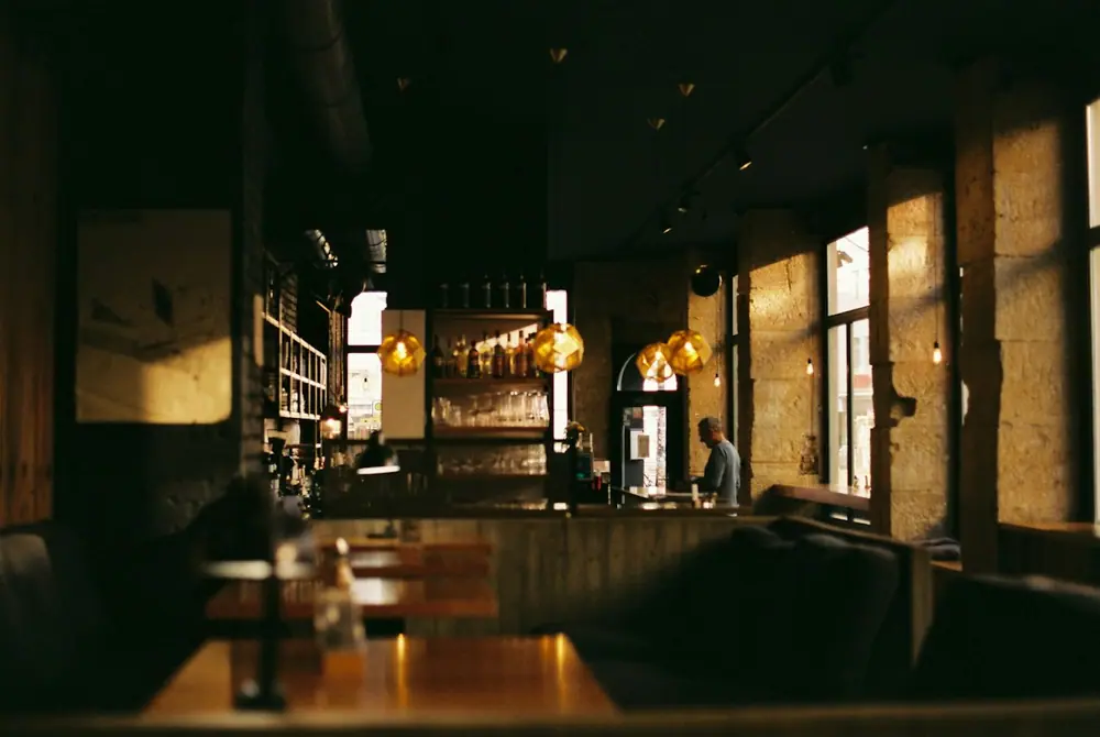 Interior en penumbra con barra de madera y mesas