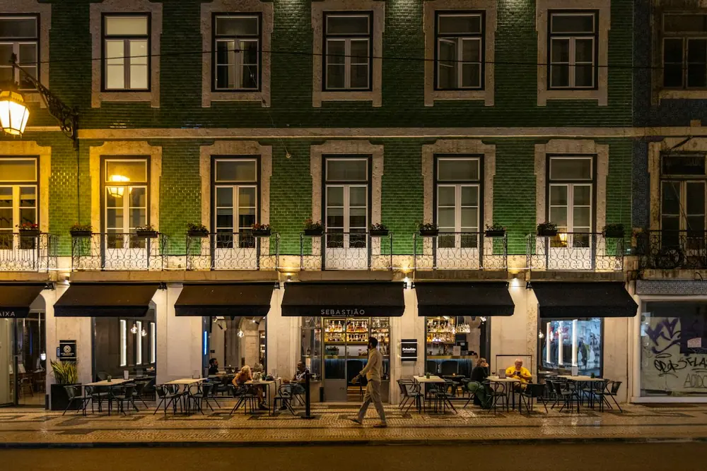 Fachada de azulejo verde en Lisboa con terraza al atardecer